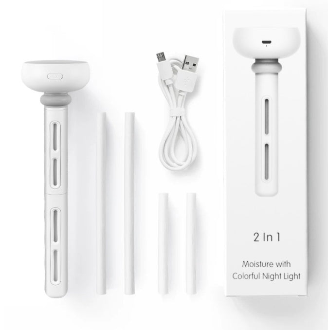 A white portable USB stick humidifier is displayed with its charging cable and filter sticks, alongside its retail box. The box highlights it as '2 In 1 Moisture with Colorful Night Light'.