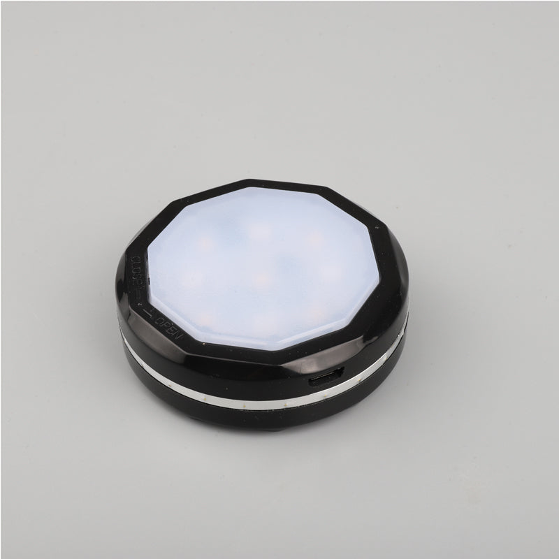 A black hexagonal wireless puck light with a white luminous top. The side shows "OPEN" and "CLOSE" text, indicating a twist mechanism.