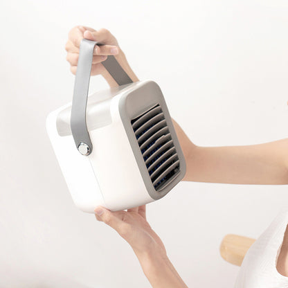 A person holds a white and gray Zainzio portable water cooling fan by its gray handle, showcasing its compact and portable design.