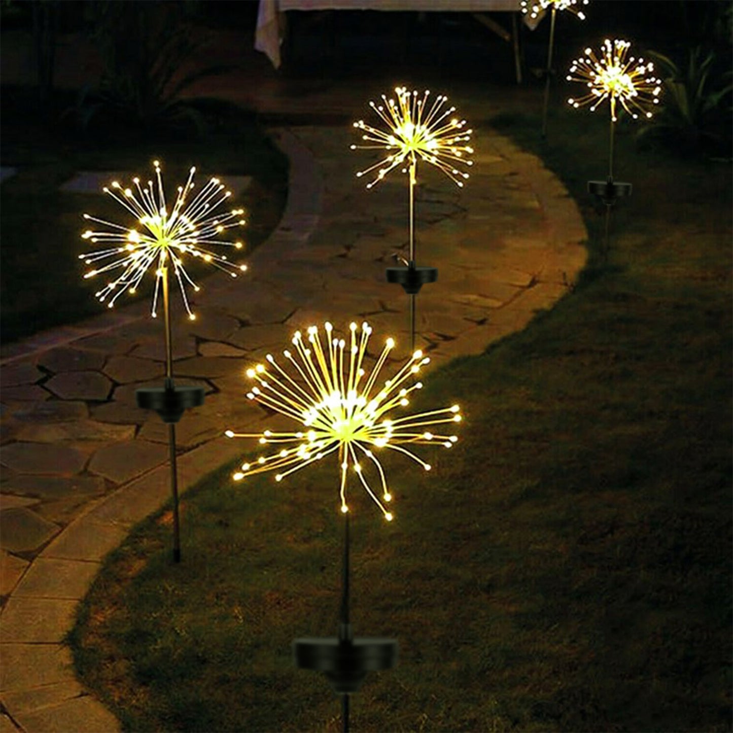 Decorative outdoor lights resembling fireworks on stakes in a garden setting.