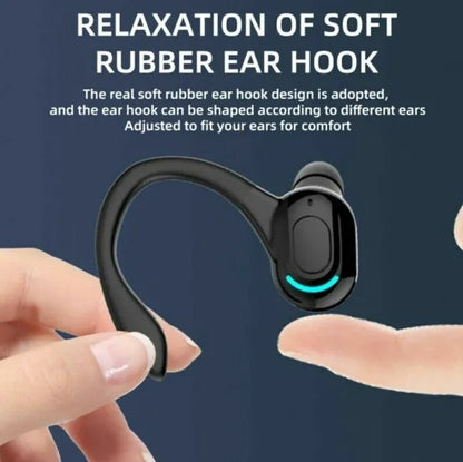 Black wireless earbud with soft rubber ear hook being held by a hand against a dark blue background.