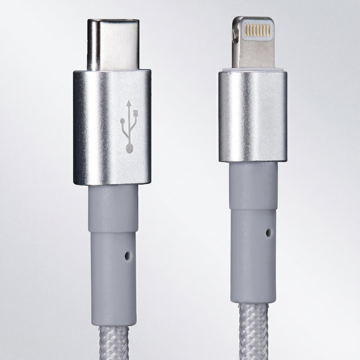 Close-up of a silver braided cable showing a USB-C connector on the left with a USB symbol, and a Lightning connector on the right.