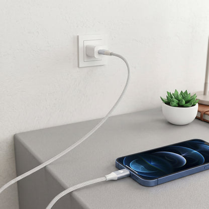 A long, silver braided Zainzio MFi Certified Lightning cable charges a blue iPhone from a wall outlet. The clean setup highlights the cable's quality and design.