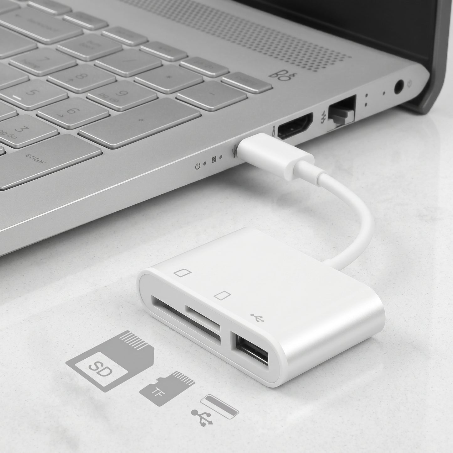 A white Zainzio 3-in-1 USB-C hub adapter, reading SD and TF cards, plugged into a silver laptop. Visible text: SD, TF.
