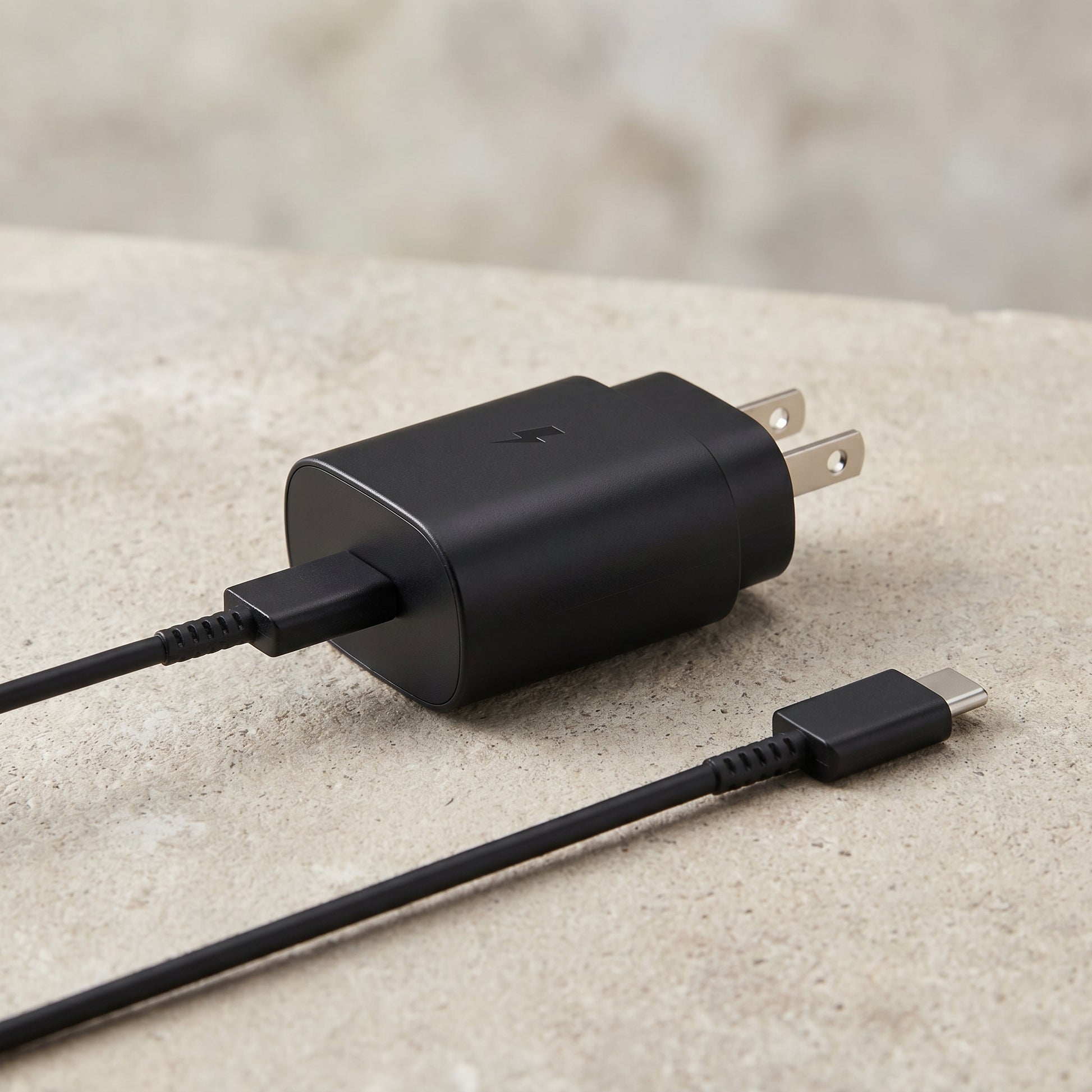 The black 25W USB-C Super Fast Wall Charger with its attached 6FT cable is displayed on a textured surface, highlighting its design.