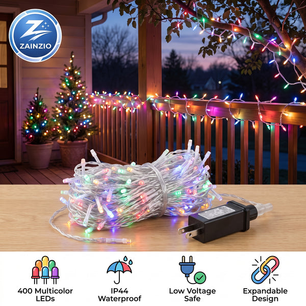 A coiled roll of multicolor LED string lights with a black power adapter sits on a wooden table in front of a decorated porch at dusk. The image includes a Zainzio brand logo in the top-left and feature icons along the bottom describing 400 multicolor LEDs, IP44 waterproofing, low voltage safety, and expandable design.
