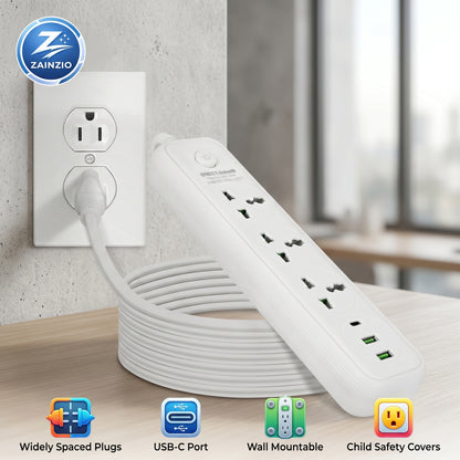 A white Zainzio power strip with a coiled 6ft cord extends from a wall outlet onto a wooden surface, highlighting its universal outlets and USB-C ports. Text: Widely Spaced Plugs, USB-C Port, Wall Mountable, Child Safety Covers.
