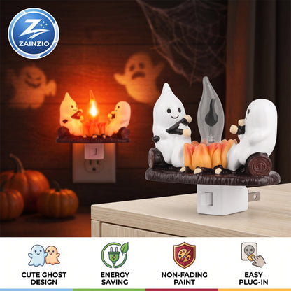 A Zainzio Halloween night light plug-in featuring two white cartoon ghosts sitting on a log and playing with a small flame. The main product is shown in the foreground on a tabletop, with a smaller inset view of the same product plugged into an outlet in the background.