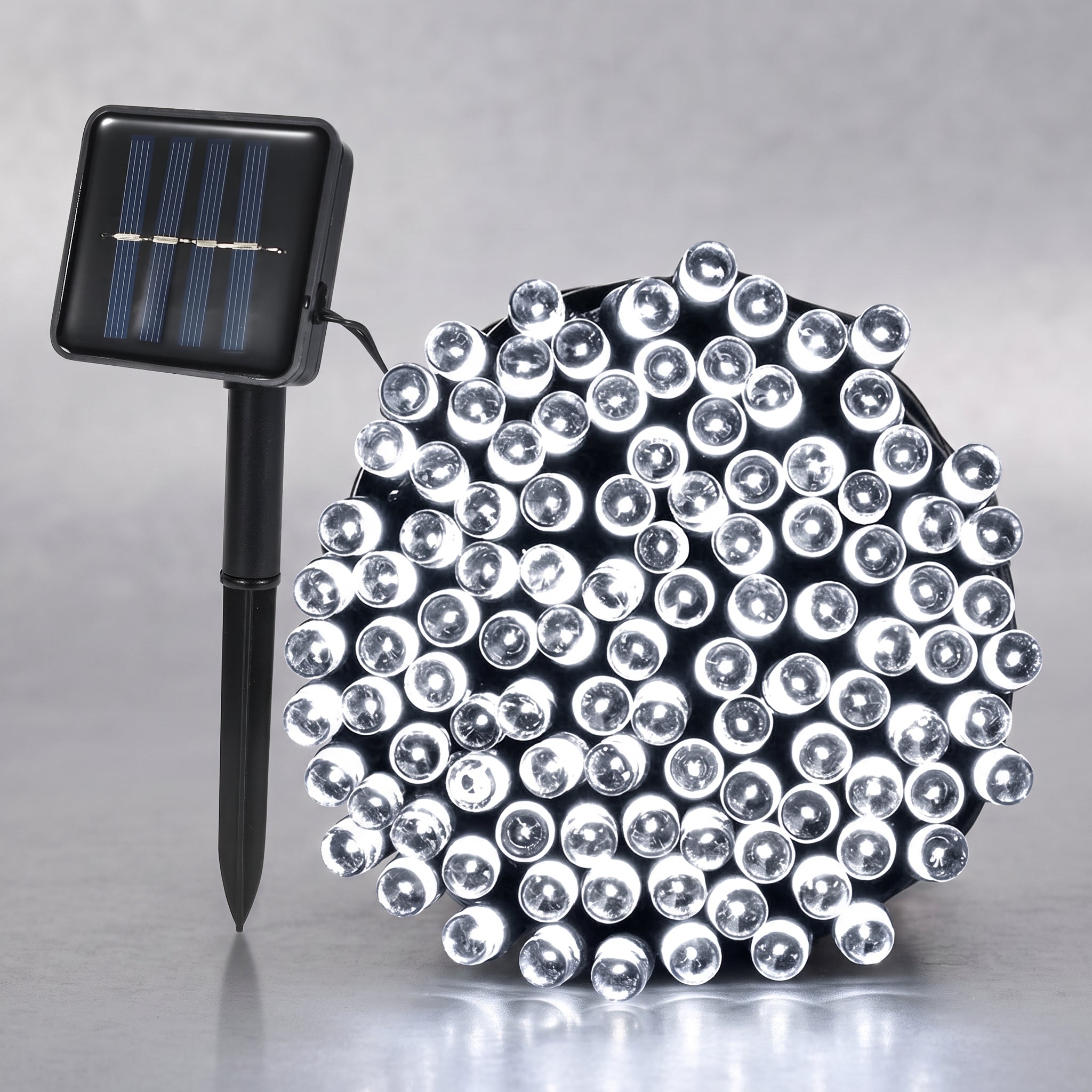 A solar-powered LED light string with a black stake-mounted solar panel on the left and a dense cluster of clear dome-shaped LED bulbs on the right, set against a neutral gray background.