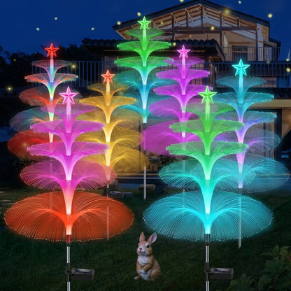 Colorful LED tree lights in a garden setting with a small rabbit figurine. Zainzio 8 Pack Solar Jellyfish Garden Lights, Color-Changing Fiber Optic Stakes.