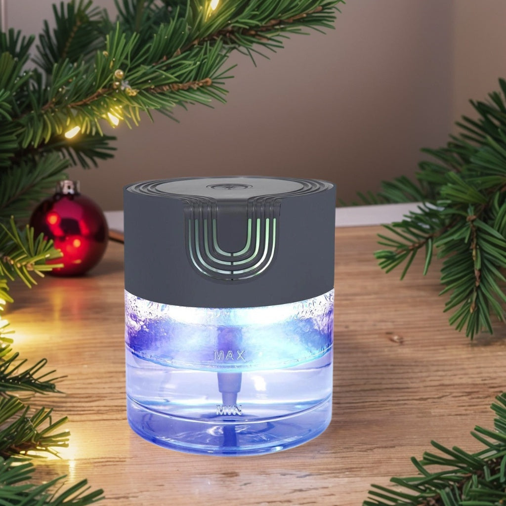 A Zainzio water-based air purifier and aroma diffuser, glowing blue, sits on a wooden surface with festive pine branches. It features visible "MAX" and "MIN" water level indicators.