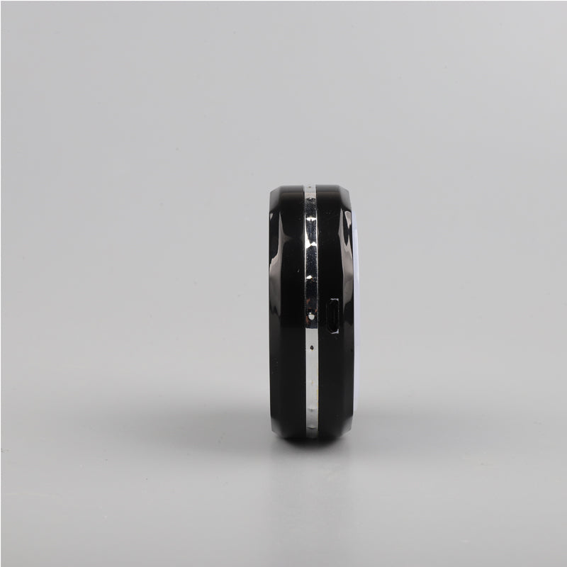 A black Zainzio puck light is shown from its side. It features a silver accent band and a small port.