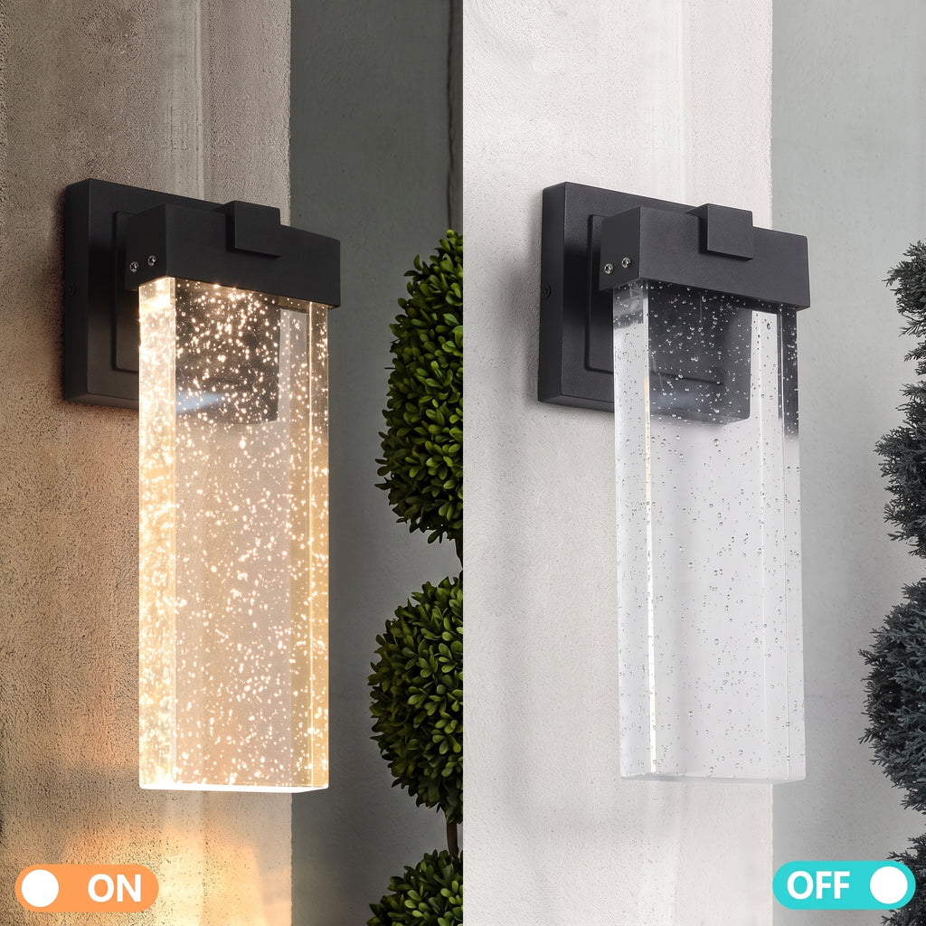 A dual-state outdoor wall sconce shown side-by-side in ON and OFF positions. The left side shows the light illuminated with warm white fairy lights inside a clear rectangular glass shade mounted on a dark black metal bracket.