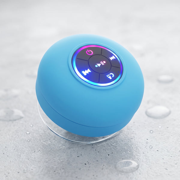 A light blue waterproof Bluetooth speaker with illuminated controls. It features a suction cup base and LED lights, resting on a wet surface.