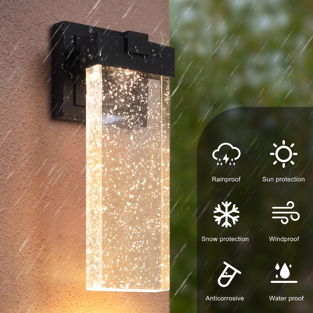 A wall-mounted outdoor light fixture with a black metal bracket and a clear rectangular glass shade filled with glowing warm light particles. The left half shows the fixture mounted on a wall in rain, while the right half shows feature icons for rainproof, sun protection, snow protection, windproof, anticorrosive, and water proof over a blurred green background.