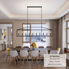A modern rectangular black metal chandelier with candle-style bulbs hanging over a dining table in a bright, contemporary dining room. A text box in the lower right specifies E12 bulb base, max wattage 40W, voltage 110V-120V, and light bulb not included.