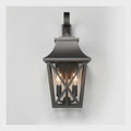 A dark charcoal outdoor wall sconce with a lantern-style frame, two visible warm Edison bulbs, and a curved mounting bracket at the top, shown against a light gray background.