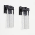 Two matching outdoor wall sconces with matte black rectangular mounts and clear seeded glass shades, shown side by side against a plain white wall.