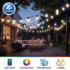 Outdoor patio string lights with warm white and multicolor bulbs hanging over a modern patio deck at dusk, with people dining in the background. A ZAINZIO logo appears in the top-left, and feature icons for app control, single-color selection, IP45 waterproofing, and linkability appear along the bottom.