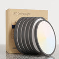 A set of round LED ceiling light panels with dark gray frames and white diffusers, shown leaning in front of their brown cardboard packaging box on a light gray background.