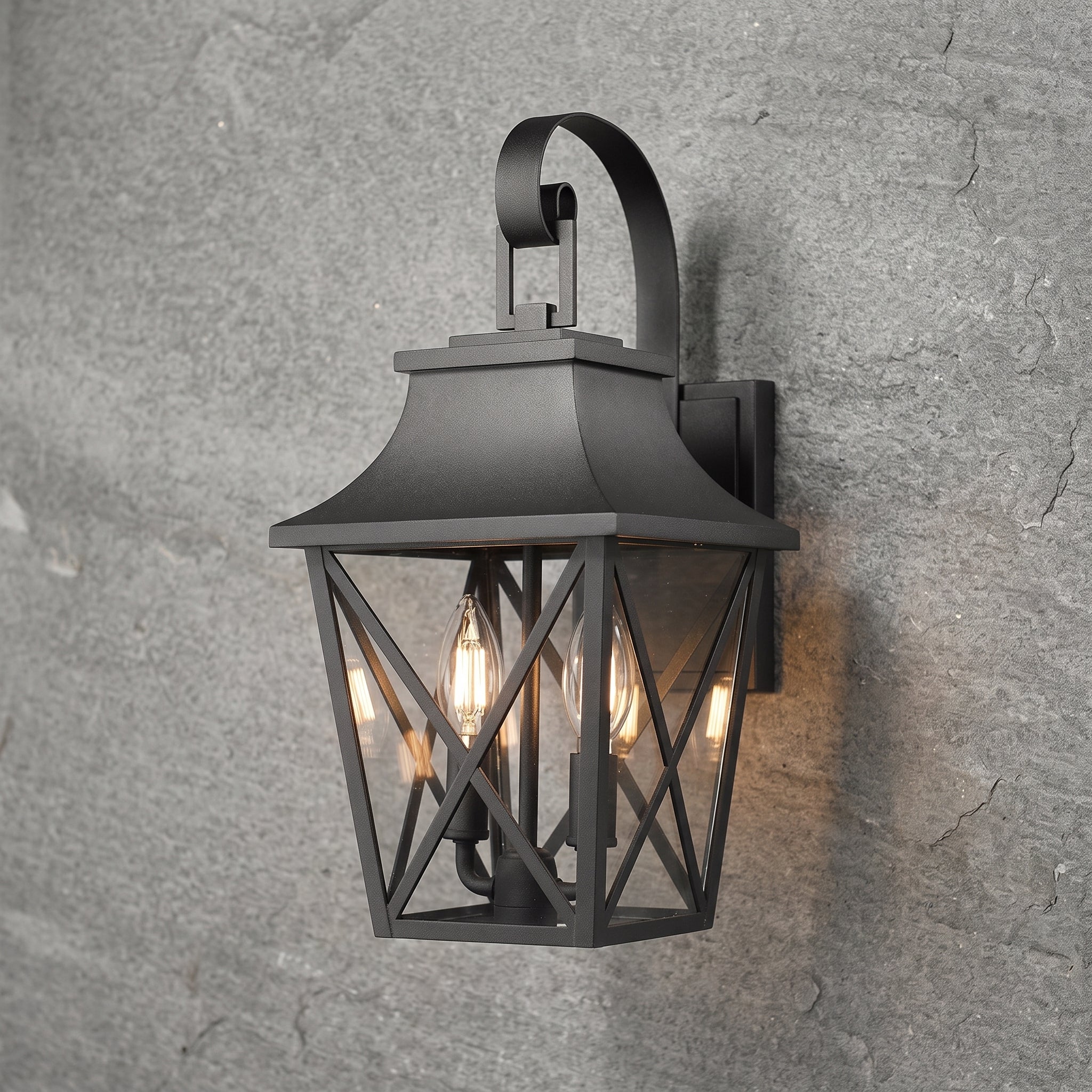 A black metal outdoor wall sconce with a lantern-style cage and three visible warm light bulbs, mounted against a textured gray stone wall.