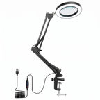 Black adjustable clamp-on USB magnifying lamp with a circular lens, shown with its USB cable and power switch on a white background.
