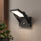 A modern black outdoor wall sconce with a built-in motion sensor, mounted on a textured beige wall next to a wooden panel and a potted green plant.