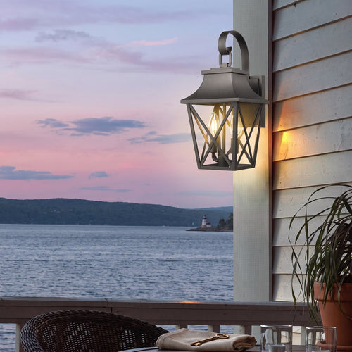 Outdoor wall lantern casting warm light over a patio at dusk