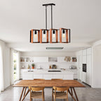 A modern rectangular pendant light fixture with copper-toned vertical frames and black metal structure, hanging over a dining table in a bright contemporary kitchen and dining room.