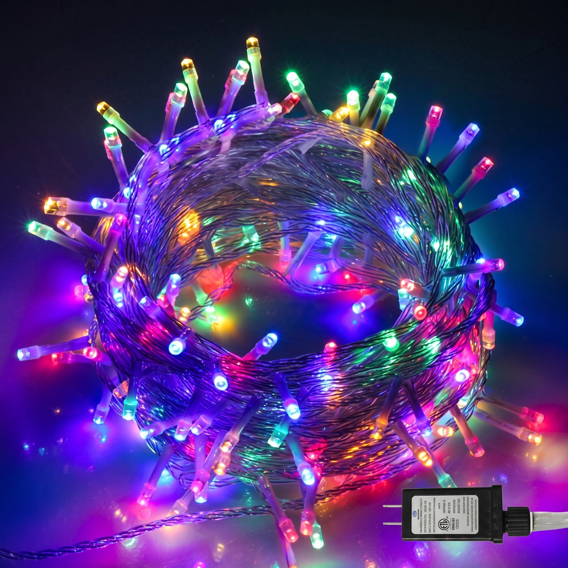 Multicolor LED fairy string lights coiled in a sphere shape with a black power adapter shown in the bottom right corner against a dark background.