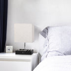 Modern bedroom with a bed and nightstand featuring a lamp and clock.