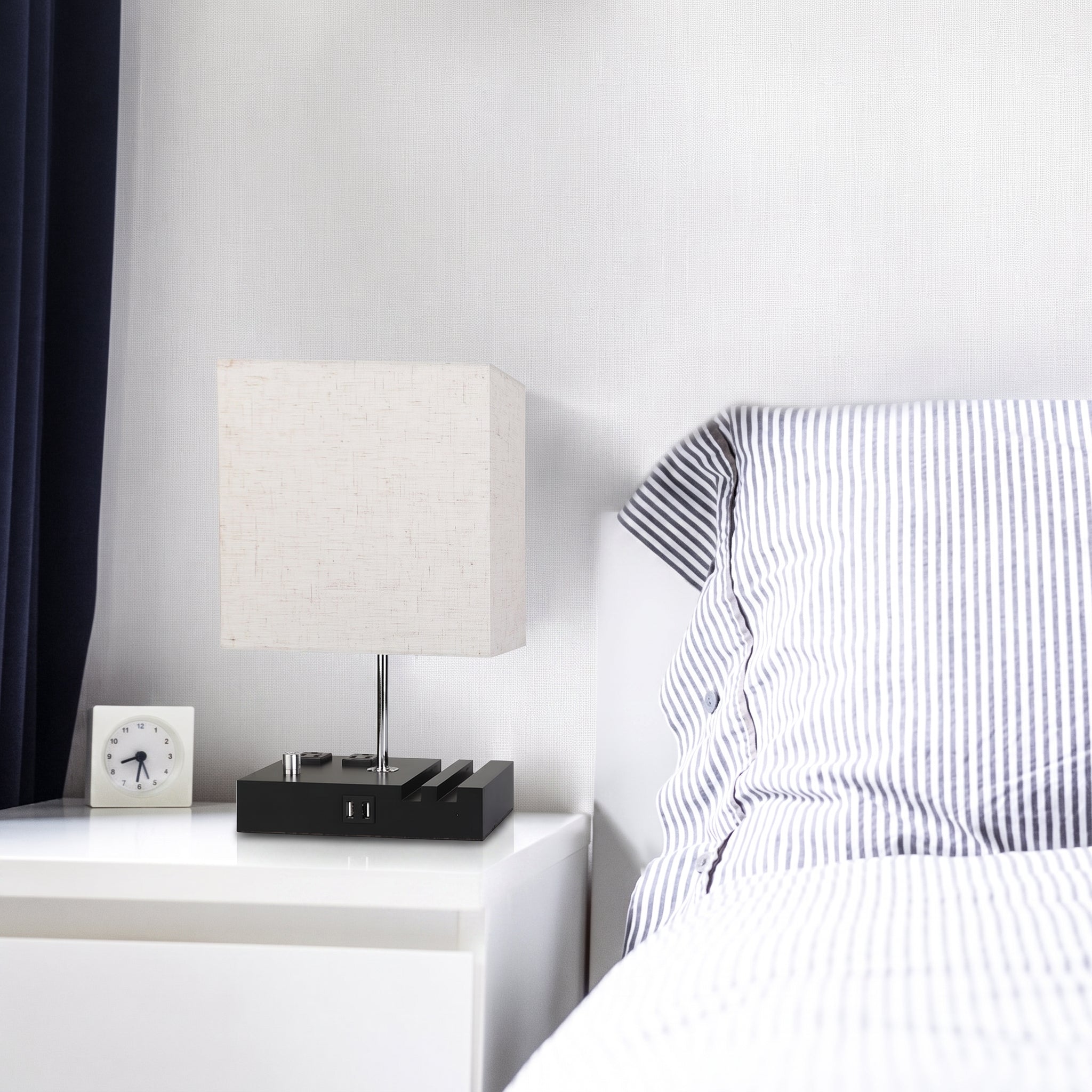 Modern bedroom with a bed and nightstand featuring a lamp and clock.