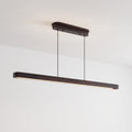 A modern linear LED pendant light in a dark bronze finish, suspended from a matching ceiling canopy against a white textured ceiling.