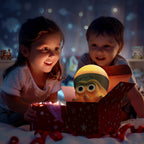 Two children sitting on the floor looking excitedly into an open gift box containing a yellow-green toy character with large eyes. The scene is warmly lit on the children's faces, with a cozy, starry bedroom background.