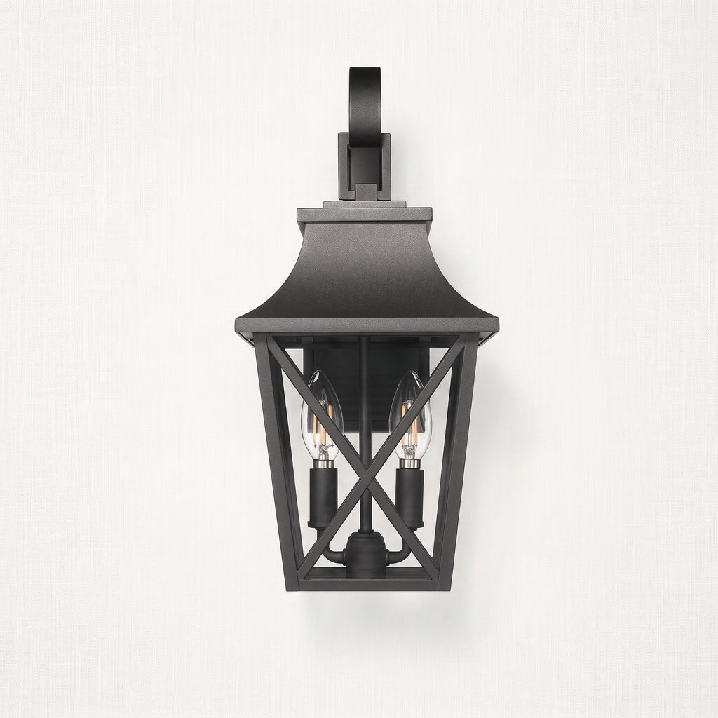 A black outdoor wall sconce with a lantern-style frame and two visible bulbs, mounted against a light textured wall.