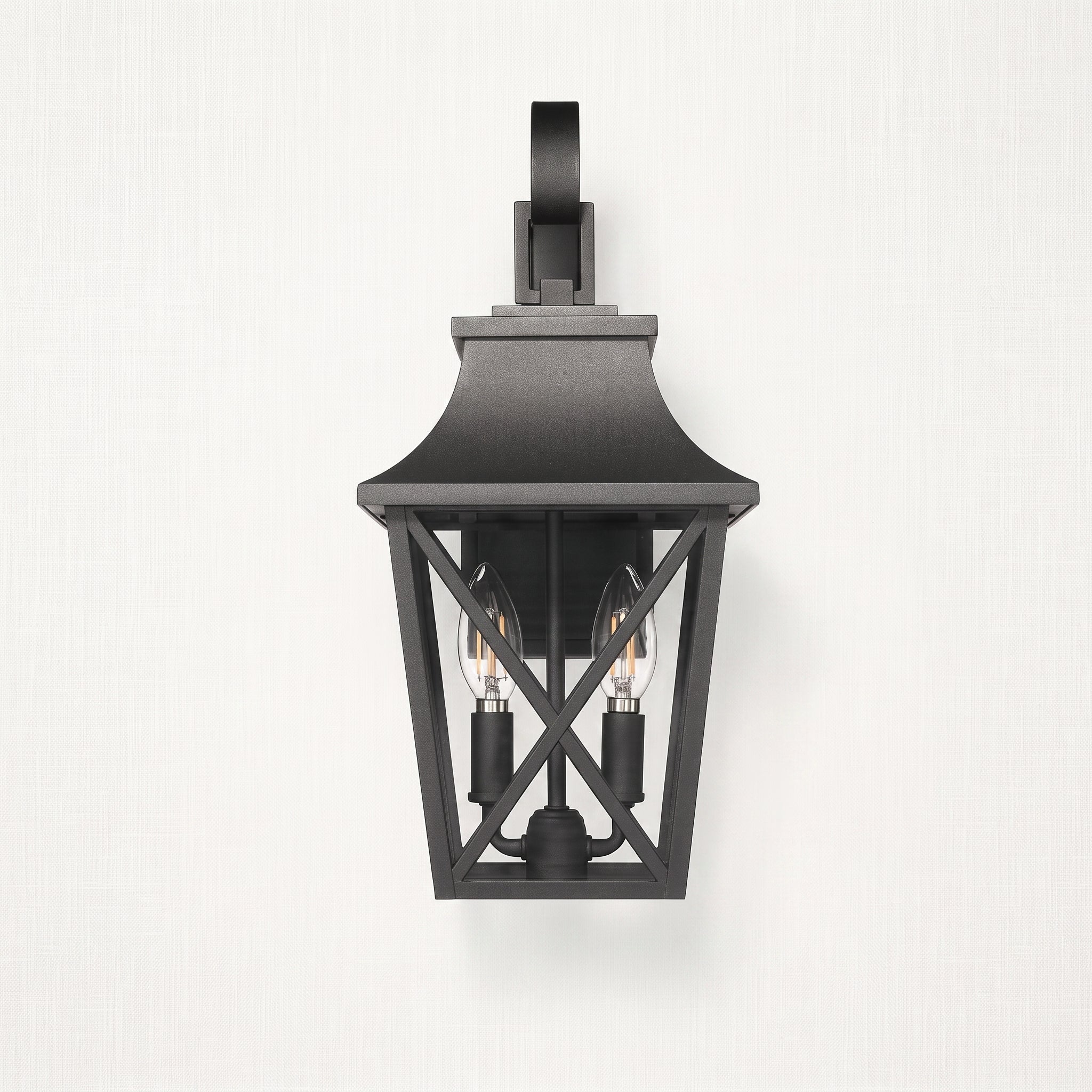 A black outdoor wall sconce with a lantern-style frame and two visible bulbs, mounted against a light textured wall.