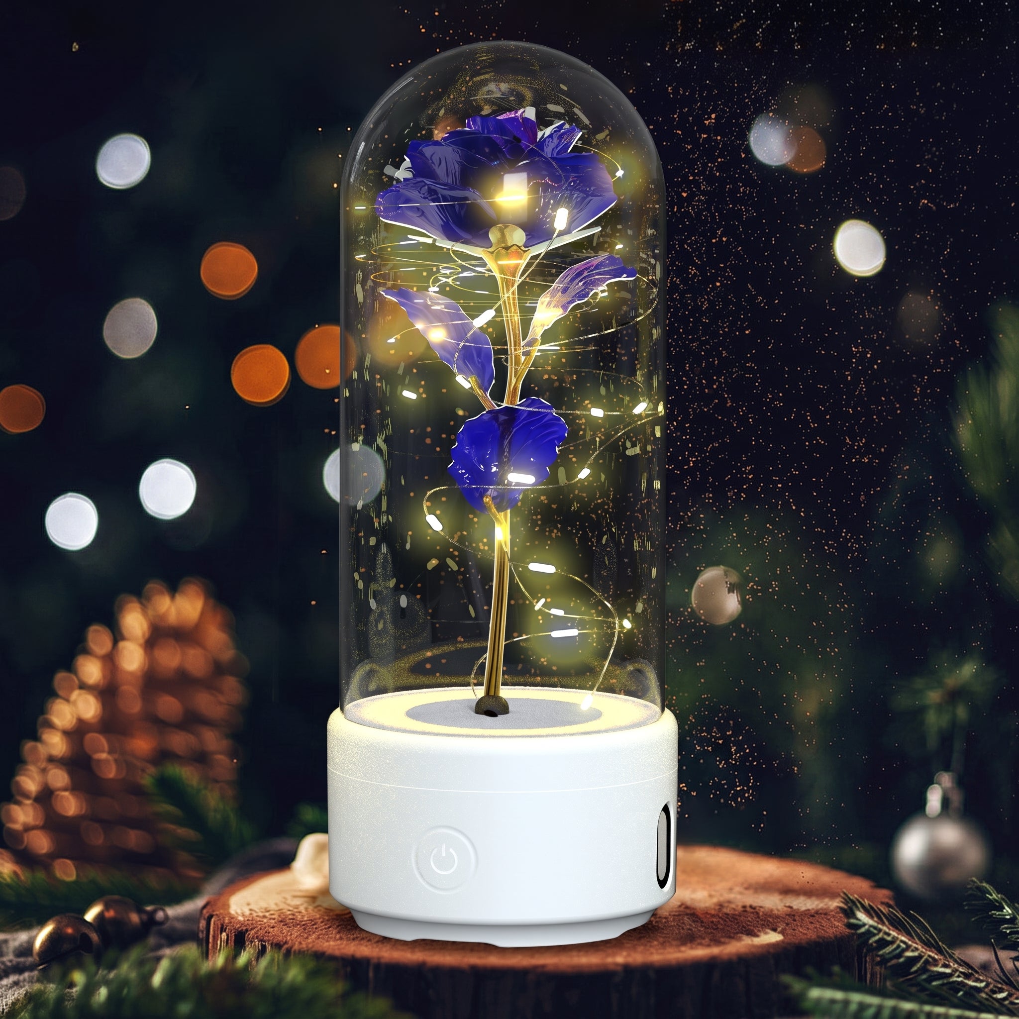 A preserved blue rose with glowing warm fairy lights inside a clear glass dome, set on a white cylindrical base. The product is photographed on a wooden surface with a blurred Christmas tree and ornaments in the background.