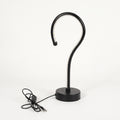 A modern black metal table lamp with a curved hook-shaped arm and a round base, shown with its power cord on a clean white background.