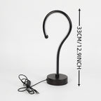 Black metal S-shaped hook lamp with a round base and power cord, shown on a light gray background with a vertical height measurement annotation of 33CM (1.29 inches).