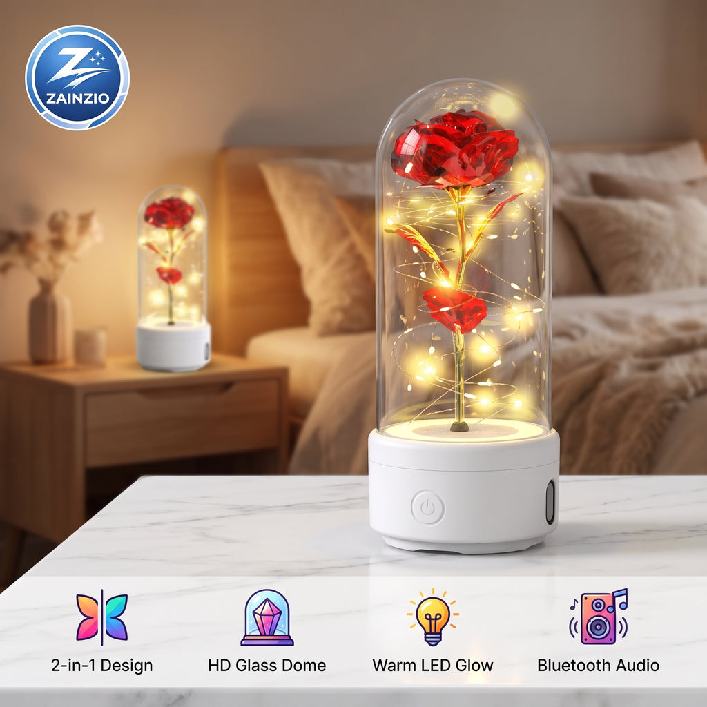 A glass dome LED lighted rose night light on a white base, shown lit on a marble tabletop in a bedroom setting with a matching smaller version in the background. Features a ZAINZIO brand logo and feature icons along the bottom.