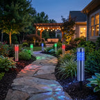 Zainzio RGB solar garden stake lights glowing in red, green, and blue along a stone path in a backyard at twilight.