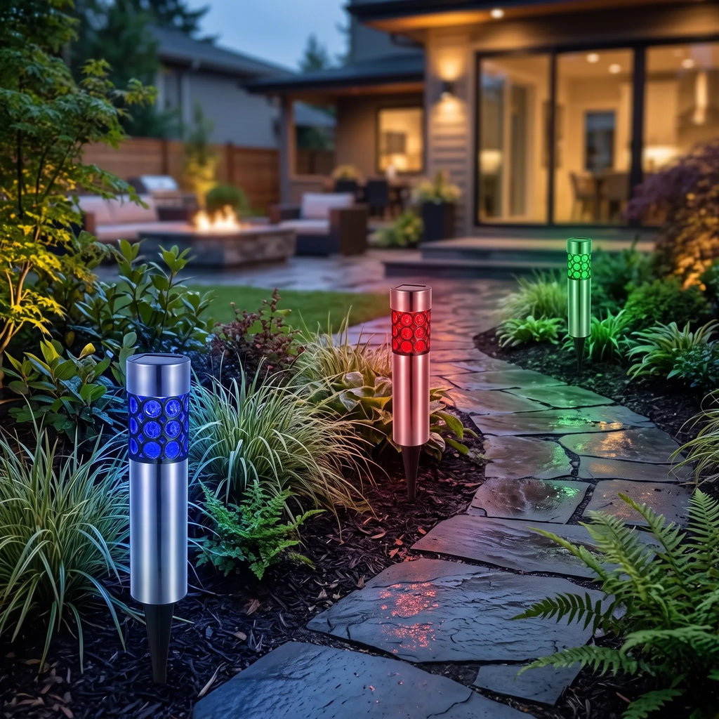 Zainzio RGB solar garden stake lights with stainless steel bodies glowing in blue, red, and green along a stone path.
