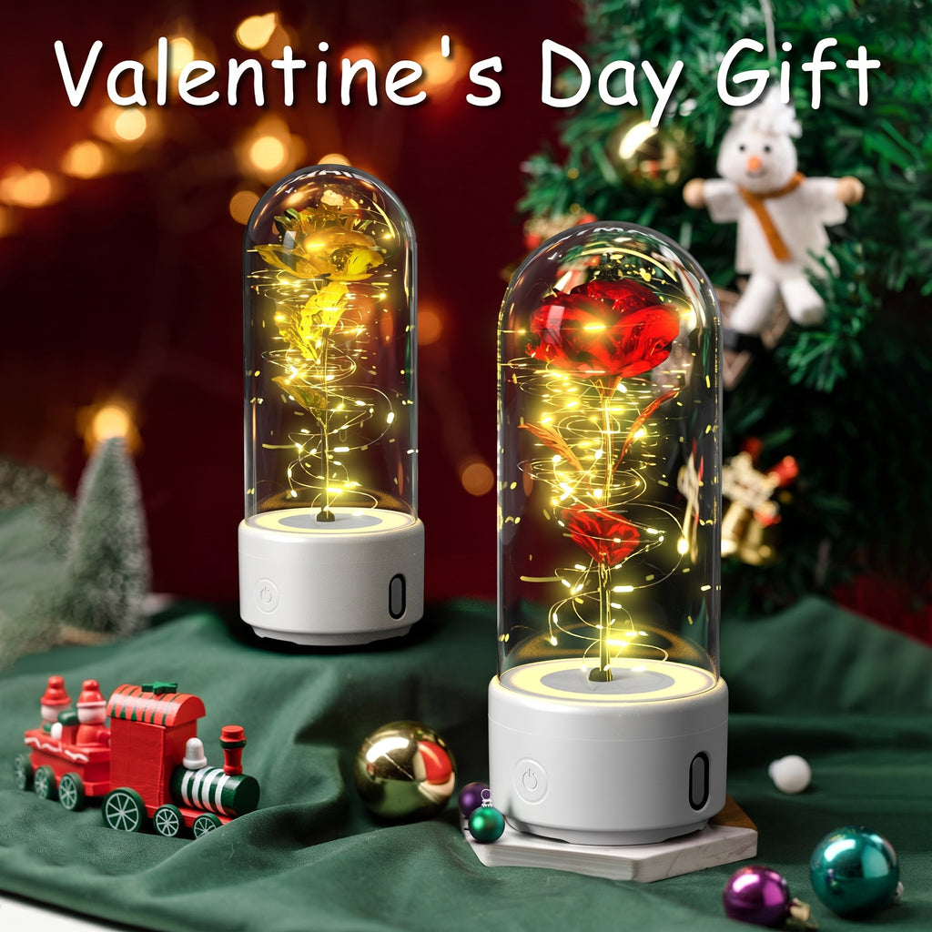Two illuminated glass dome flower lamps with white bases are displayed on a green fabric surface with Christmas decorations, including ornaments, a small train, and a tree. Large text at the top reads 'Valentine's Day Gift'.