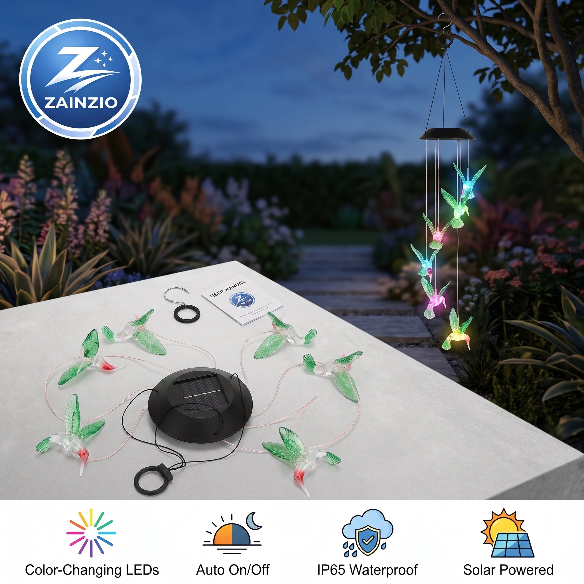 Solar-powered hummingbird string lights displayed on a patio table at dusk, with a hanging wind spinner also shown outdoors. The set includes a black solar panel, multiple green hummingbird-shaped lights, and a small instruction card.