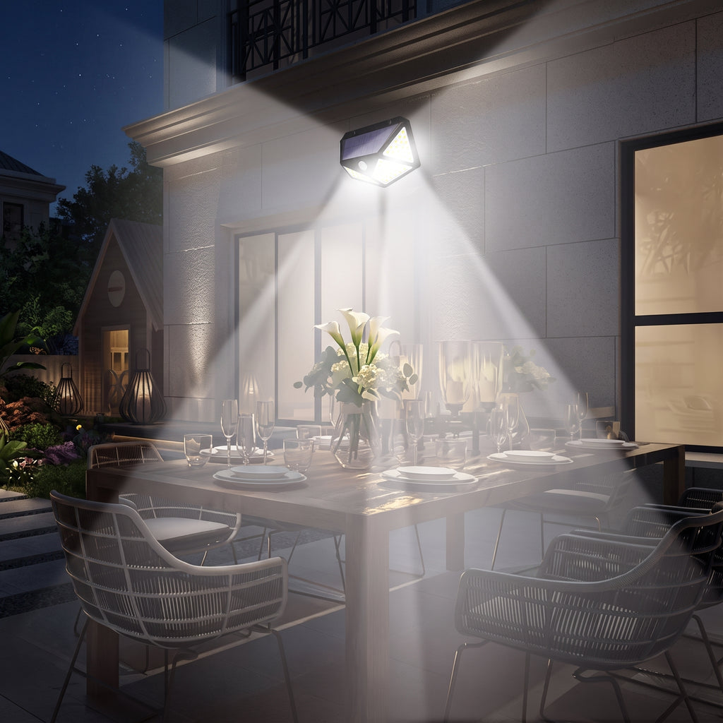 Outdoor wall sconce lighting a dining table at night, casting a bright beam of light across a set dining set on a patio beside a modern house.
