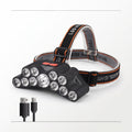 A black LED headlamp with multiple clear lenses and a black adjustable strap with orange stitching, shown on a white background with two small USB charging cables below it.